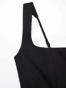 Détail de la boucle en métal réglable et bretelles asymétriques sur une robe noire plissée