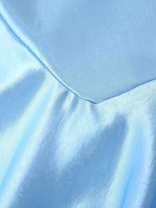 Détail du tissu en satin bleu clair avec col bénitier et texture soyeuse et brillante