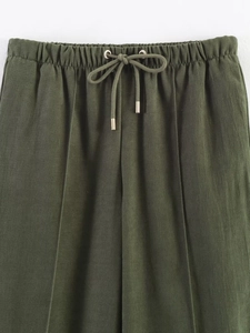 Detail of dark green elastic drawstring waistband with premium metallic aglets on trousers