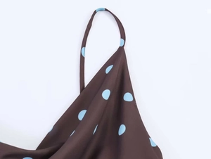 Detailed macro shot of blue polka dots on dark brown silk-like dress with thin straps