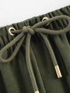 Detailed macro view of olive green jogger waist with elastic band and gold metal drawstring