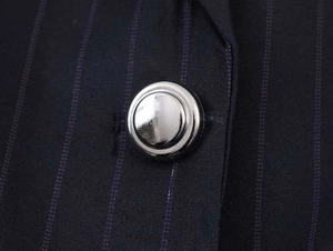Detailed close-up of dark blue pinstripe fabric and smooth silver metallic button texture