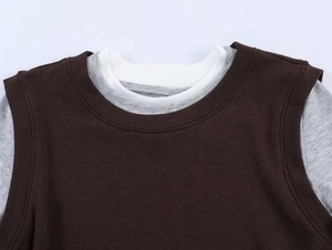 Detailed close-up of the layered contrast neckline on a brown knit long sleeve top