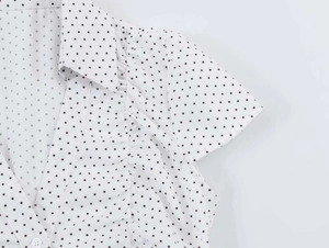 Detail of V-neck collar and cap sleeves on a white polka dot retro button-up shirt