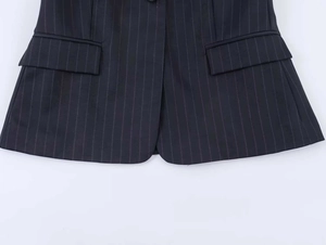 Detail of dark blue pinstripe blazer featuring two symmetrical flap pockets and clean seams