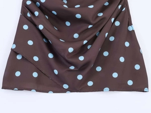 Detail of polka dot dress fabric with blue dots on brown background and draped hemline