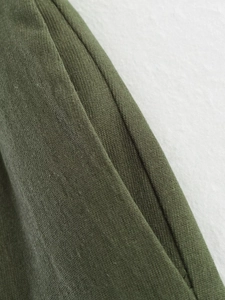 Detailed macro view showing the dark green ribbed knit fabric and precise stitching