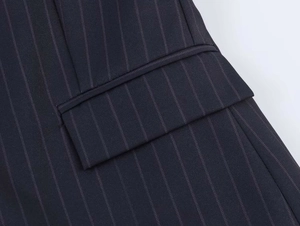 Macro shot of flap pocket detail on dark pinstripe suit blazer with fine stitching
