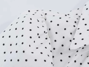 Detail view of V-neck collar and black polka dot pattern on white vintage blouse