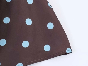 Detailed view of polka dot print fabric on dress with blue spots on dark brown base