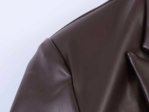 Close-up of dark brown PU leather jacket showing fine lychee texture and stitching