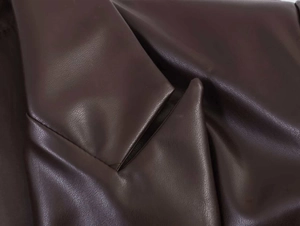 Close-up of dark brown faux leather jacket showing detailed lychee grain texture and seams