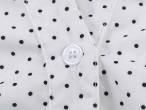 Detailed macro view of white shirt fabric with black polka dots and a resin button