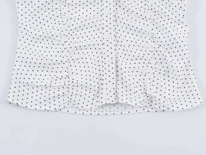 Detail shot of white polka dot blouse featuring round buttons and textured fabric