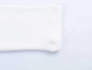 Detailed macro view of the white ribbed knit texture and stitching on long sleeve hem
