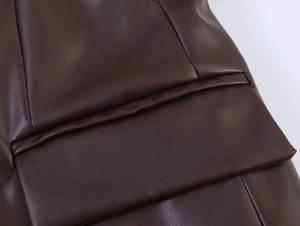 Close-up detail of dark brown PU leather blazer showing pocket flap and stitching texture