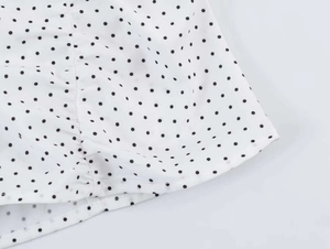 Close-up of white fabric with black polka dots showing neat hemmed edge and stitching