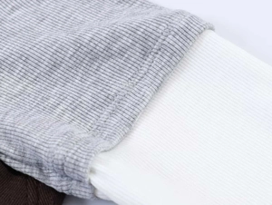 Macro detail of ribbed knit fabric texture and color contrast stitching on long sleeve tee