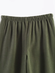 Detail showing elastic waist design and dark green fabric texture of casual trousers