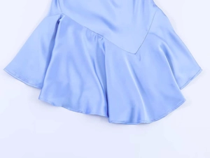 Detail eines hellblauen Satinkleids mit asymmetrischem Rüschensaum und Seideneffekt