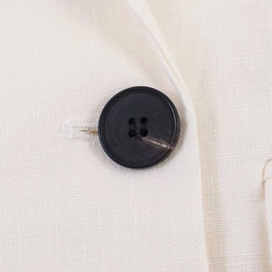 Macro shot of texture detail on white linen blazer with premium black resin button