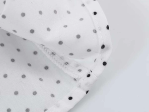 Close-up of white fabric with black polka dots showing high-quality stitching and texture