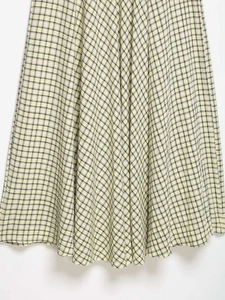 Detail of yellow and black plaid pleated skirt with a textured seersucker fabric finish