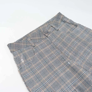 Detail view of high waist plaid trousers showing textured fabric and single button closure