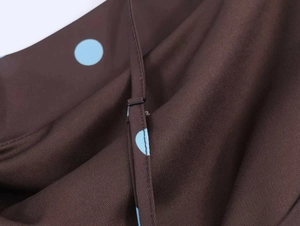 Detail of adjustable strap and blue polka dots on brown twill fabric dress