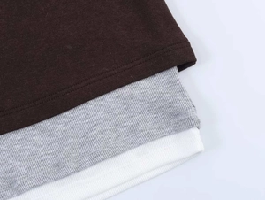 Macro detail of layered ribbed and plain knit fabrics in brown, gray, and white tones