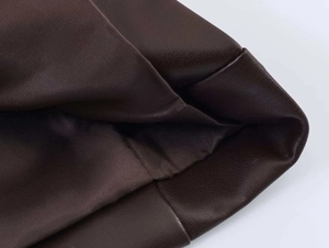 Detailed macro view of dark brown PU leather grain and inner fabric lining of the blazer