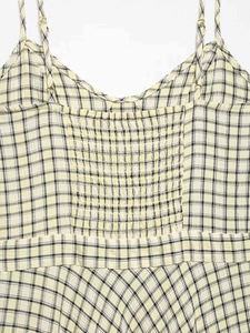 Detail of yellow checkered midi dress showing adjustable gold buckles and smocked back design