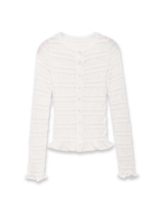 Close-up of white smocked knit cardigan featuring ruffle cuffs and delicate button detailing