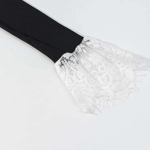 Dettaglio di polsini neri con bordo in pizzo bianco a balze e design a campana