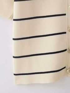 Gros plan détaillé sur le tricot crème à rayures noires et boutons dorés en métal gaufré