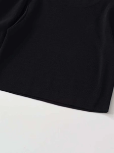 Detailansicht der feinen Strickstruktur und des Ausschnitts vom schwarzen Strickoberteil