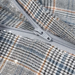 Close-up of gray plaid fabric with shimmering sequins and premium metal zipper detail