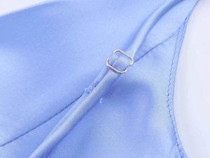 Detail eines verstellbaren Trägers mit silberner Metallschnalle an hellblauem Satin-Kleid