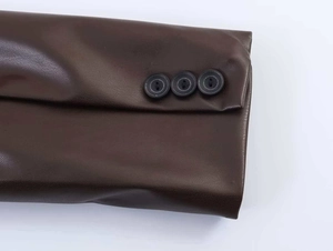 Detail of dark brown faux leather jacket cuff with three black buttons and lychee texture
