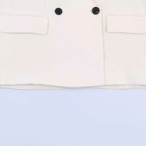 Detail of white linen blazer featuring black resin buttons and flap pockets