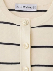 Détail d'une veste en maille rayée avec boutons dorés à ancre et étiquette de marque