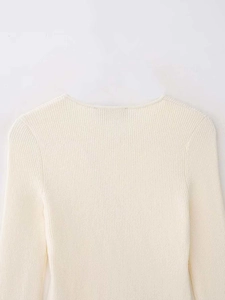 Gros plan d'un pull en maille côtelée blanc crème montrant la texture fine du tissu doux