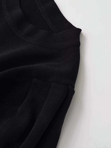 Detaillierte Nahaufnahme eines schwarzen Strickoberteils mit Rundhalsausschnitt und Ärmelnaht