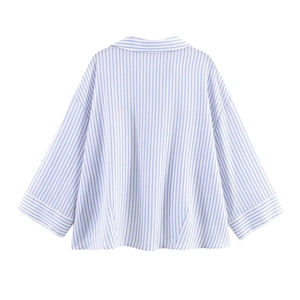 Detail view of the back of a blue white striped oversized shirt with drop shoulder design