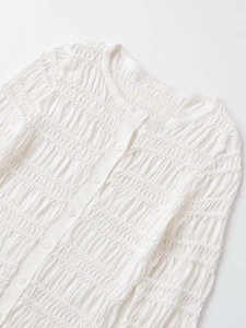 Close-up of the white pleated knit cardigan showing vertical texture and buttons