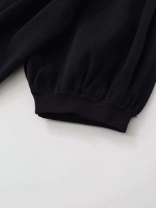 Nahaufnahme von schwarzem Strickstoff mit feiner Textur und geripptem Bündchen