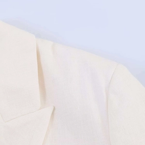 Close-up detail of notch lapel and linen-textured fabric on white summer blazer jacket