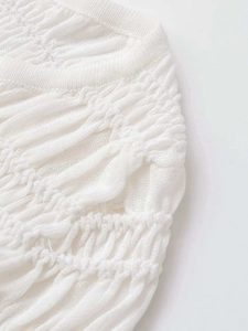 Detailed view of white pleated knit cardigan featuring intricate texture and ribbed neckline