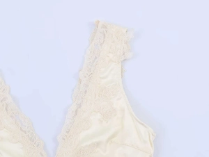 Dettaglio dello scollo a V con pizzo e tessuto in raso satinato color champagne lucido