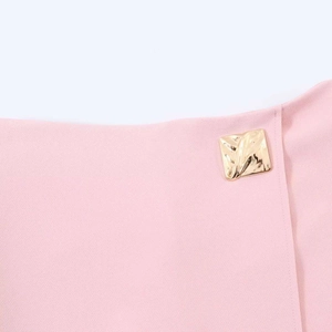 Detail of pink skirt waist with a textured square gold buckle on fabric